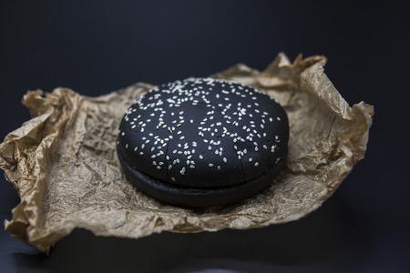 Black bun for the Burger close-up on paper on a dark backgroundの写真素材