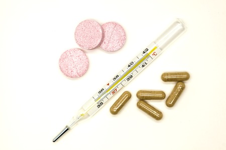 Old mercury medical thermometer with pills closeup on white background.