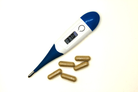 Modern electronic thermometer with pills closeup on white background.の写真素材