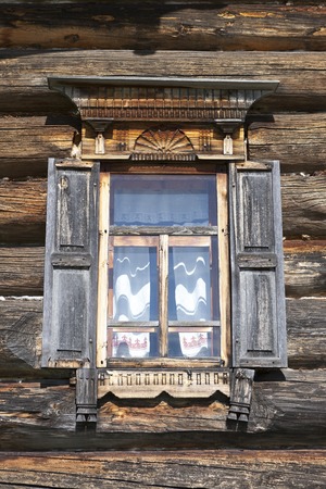 Old window with open shutters glass with a blue sky on the background of the wooden wall of the countryside log house.の写真素材