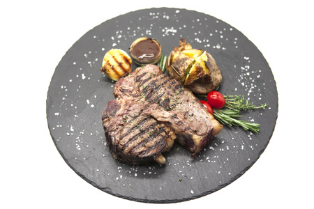 Juicy beef steak medium rare on a stone plate with cherry tomatoes and a large sea salt.の写真素材