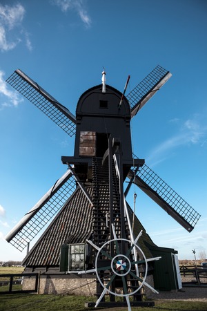 Dutch windmill, rear view, large blades, the steering wheel controls. The mill is on the canals of Holland near the city RotterdamTraditional dutch windmill near the canal. Netherlands. Old windmill stands on the banks of the canal, and water pumps. Whiteの写真素材