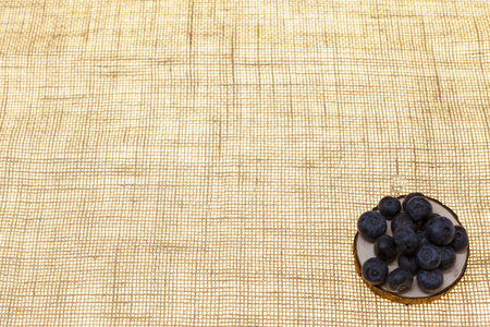 Blueberries on a wooden plate on a linen background closeup.Background for confectionery, cafe fresh berries for pastryの写真素材