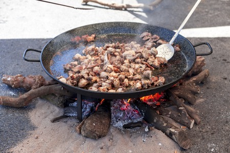 Fried chicken legs. Preparation of chicken paella.national Spanish dish of paella in a large skillet is cooked on an open fire, at the stakeの写真素材