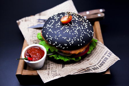 A juicy black burger. Burger with marble beef, fork with knife and chili sauce.の写真素材