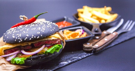 Delicious set: burger, French fries, curry sauce, chilli sauce fork and knifeの写真素材