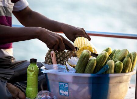 Fruit seller in India. Ripe pineapples, cucumbers, salt spices. Traditional delicacy in india goa...