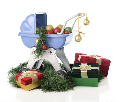 A child's blue doll buggy surrounded by Christmas garland and wrapped gifts and filled with colorful...