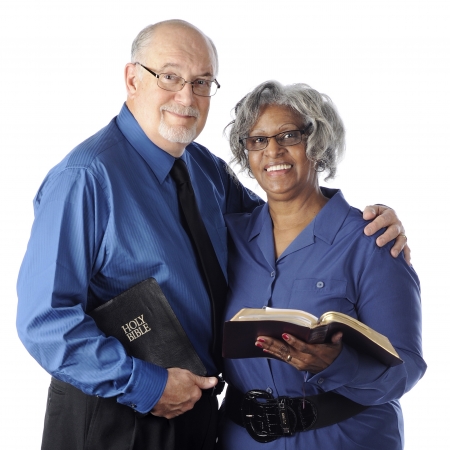 A mixed race senior couple happily holding their Bibles.  On a white background.の写真素材