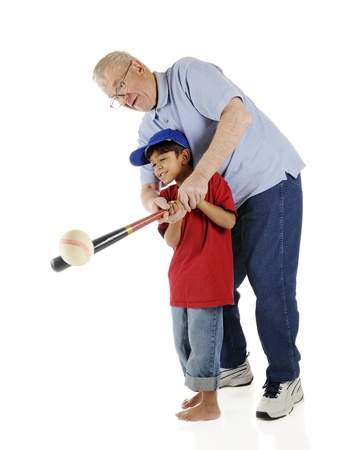 A senior and his preschool grandson working together to successfully bat a baseball.  On a white background.の写真素材