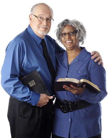 A mixed race senior couple happily holding their Bibles.  On a white background.の写真素材