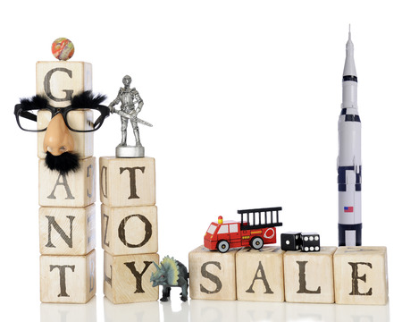 Rustic alphabet blocks arranged to say "Giant Toy Sale"  surrounded by a variety of small toys.  On a white background.の写真素材