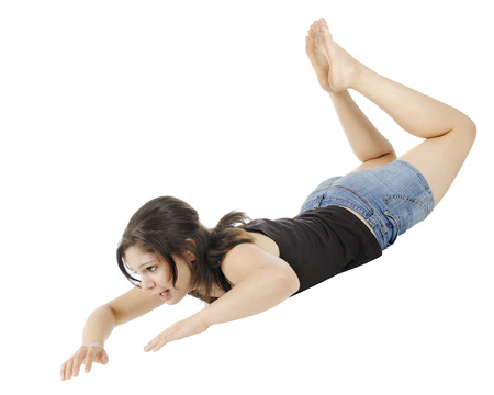 An attractive young teen moving down through the air hands and head first.  On a white background.の写真素材