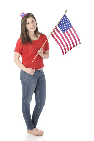 A pretty, barefoot young teen carrying an American flag while wearing a tiny Uncle Sam hat.  On a white background.の写真素材