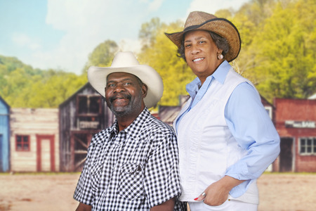 A senior sitting cowboy by his standing wife in an old western town.の写真素材