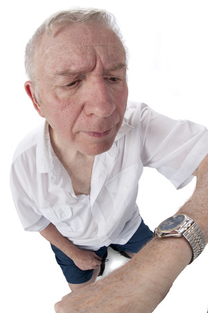 Fish-eye image of a stressed senior man checking his watch.  On a white background.の写真素材