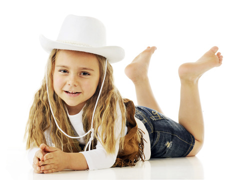 A barefoot cowgirl  happily relaxed on her belly.  On a white background.の写真素材