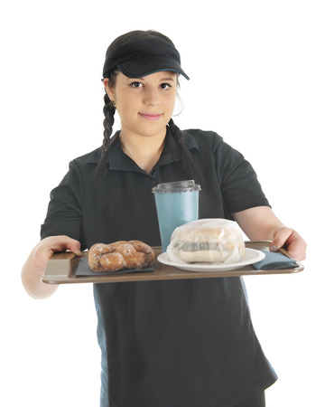 A pretty young watefress handing the viewer a tray with a wrapped breakfast sandwich, a twisted donut and cup of coffee.  On a white background.の写真素材