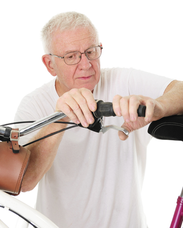 Closeup of a senior man working on his granddaughter's bike's hand brake.  On a white background.の写真素材