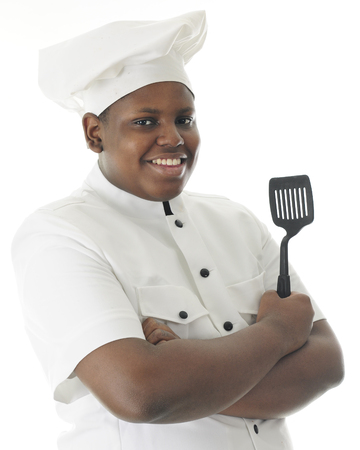 Half-length image of a proud teen chef happily holding a spatula.  On a white background.の写真素材