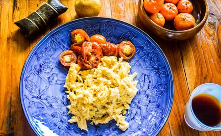 Rich breakfast with scrambled eggs, coffee, fruits and sticky riceの写真素材