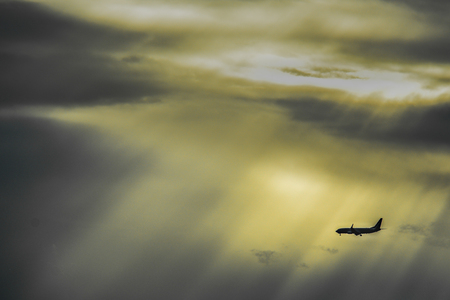 An airplane flying through the evening sunbeamsの写真素材