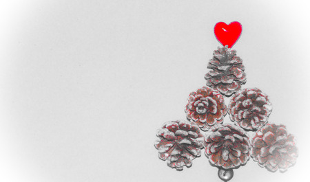 Blurred on purpose Christmas theme with space for text and greetings. Acorns shaped in a Christmas tree with a red heart on the topの写真素材