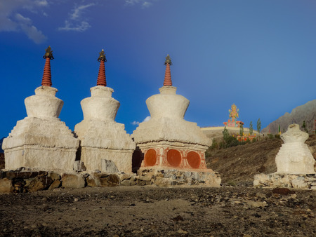 small stupas in the foreground with the giant Buddha statue from the Diskit Gompa in the background, Diskit, Diskit valley, Ladakh, Indiaの写真素材
