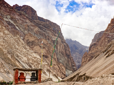 Three small black and red gompas stand at the beginning of a mountain route through two rocks. Indiaの写真素材