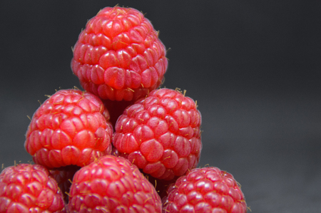 A close-up of arranged red raspberries on black background