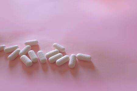 Vitamin C tablets against a pink pastel colored background