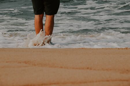 Conceptual photo of a man standing on the beach showing concept of finding peace, supporting mental health and social distancing during the covid-19 outbreakの写真素材