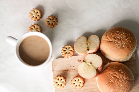 Freshly baked bread buns and biscuit with apples and coffee showing the cozy feeling of having breakfast at home as a way to cope and support mental health during the covid-19 quarantineの写真素材