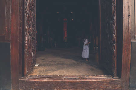 A woman in a white dress in the doorway of Baan Dam Museum or Black House in Chiang rai, Thailandのeditorial素材