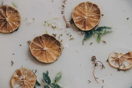 Close up of a therapeutic milk bath filled with dried lemon slices and other herbs for spa, beauty and wellnessの写真素材