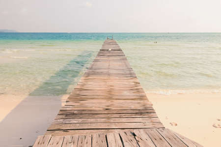 Scenic view of a wooden boardwalk leaving to the white sandy beach of Koh Rong Samloen Island, a popular summer getaway destination in Cambodiaの写真素材