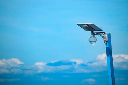 A solar-powered lamp post against the blue sky showing renewable energy alternative and sustainable lifestyleの写真素材