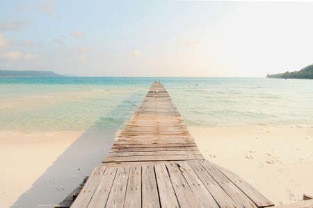 Scenic view of a wooden boardwalk leaving to the white sandy beach of Koh Rong Samloen Island, a popular summer getaway destination in Cambodiaの写真素材