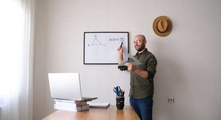 The distance education teacher teaches his students from home with a leptop camera.