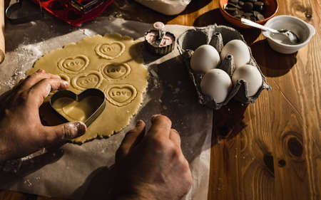 cutting dough with a mold. Romantic man in the kitchen is preparing cookies.の写真素材