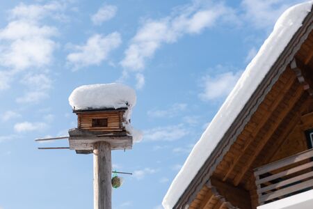 Homemade wooden bird's feeder in winter, under snow.の写真素材