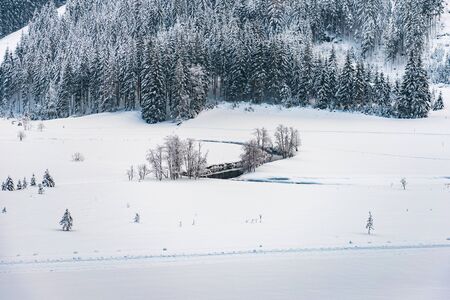 Winter mountain landscape in the Alps. The winding river, trees and mountains covered with snow.の写真素材