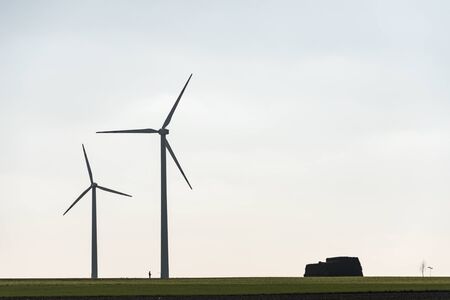 Two wind farms and a human silhouette showing the scale of windmill and man. All on the background...