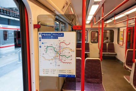 Prague metro map seen from inside the subway car. Schematic plan of the red, green and yellow metro lines. Platform visible outside, red tubes and chairs inside.のeditorial素材