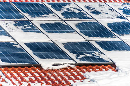 House roof covered with solar panels in winter. Electricity from the sun during winter. Sunny day, blue skyの写真素材