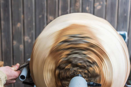 Turning wooden bowls on a lathe. The close up view of spinning the lathe machine. Man with a chisel and shavings flying off.の写真素材
