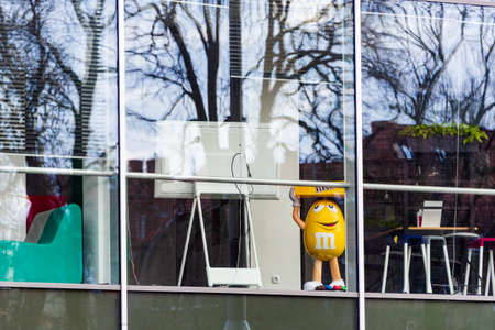 The big, yellow figure of MM's alone in empty office building during the corona virus pandemic. This is character mascot of chocolate brand m & m's produced by Mars, Incorporated.のeditorial素材