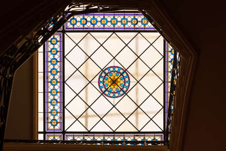 A colorful stained glass window placed on the ceiling, composed of round and square glass tiles illuminating the interior of the stairs.の写真素材