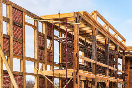 Reconstruction of an old building with a skeleton half-timbered wall structure, wooden and brick with plastered fields. Old poles, supports and new woodwork are clearly visible.の写真素材