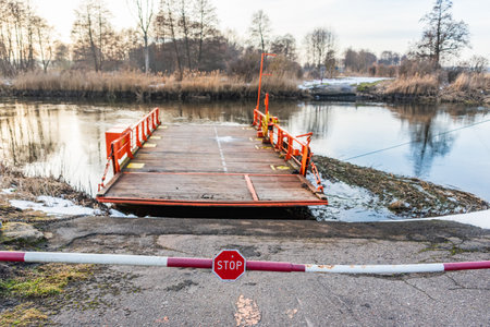 Orange river ferry. Stop sign and barrier before entering the ferry crossing on the river. Late winter afternoon, snow still visible on the river bank.の写真素材